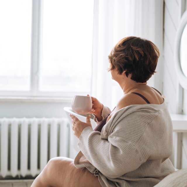 Woman relaxing at home by a bright window with a cup of tea