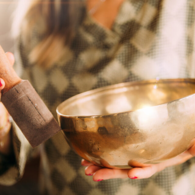Woman holding a singing bowl and mallet used in sound therapy