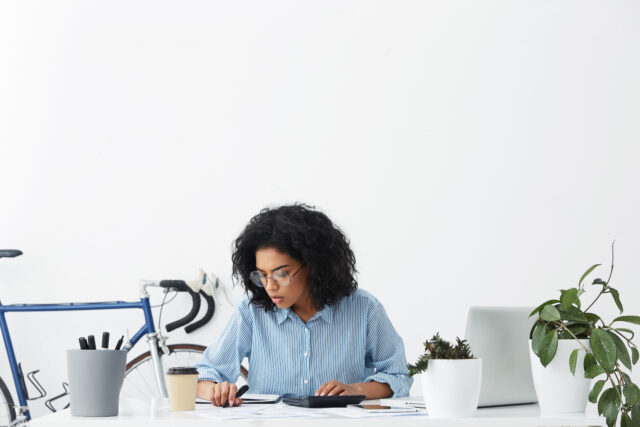 Woman focused on paperwork and a calculator at her desk